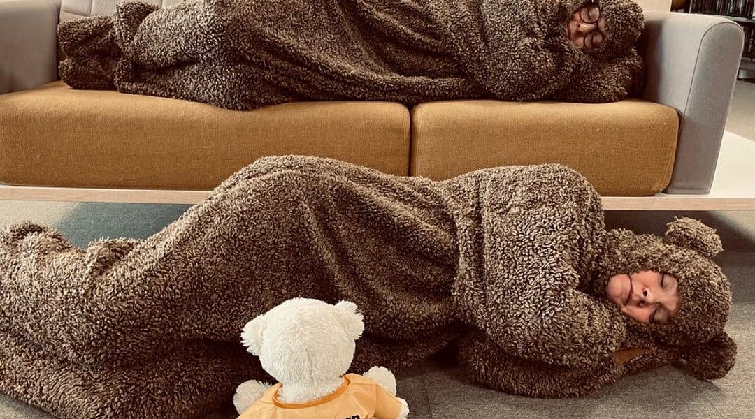 To personer utkledd som bamser ligger å sover